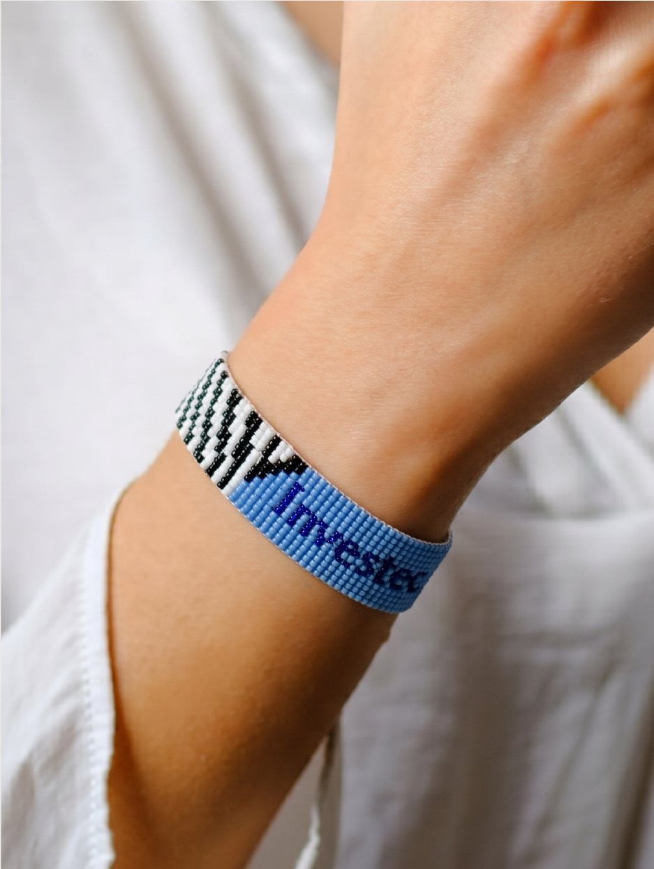 A custom loom bracelet beaded with a client's name, worn on the wrist