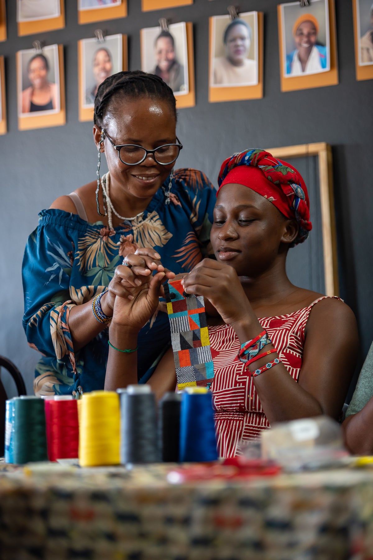 A Kioni artisan beading at home while her daughter watches