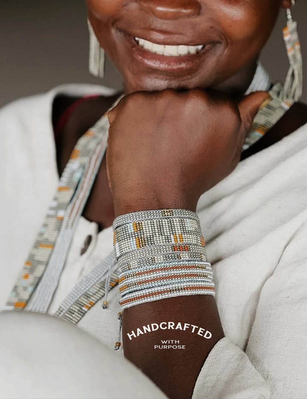 A smiling Kioni artisan wearing stacked loom bracelets